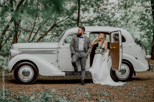 The bearded groom and beautiful bride. Retro car.
