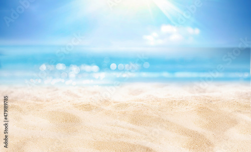 Fototapeta Naklejka Na Ścianę i Meble -  Natural blurred defocused background for concept summer vacation. Nature of tropical summer beach with rays of sunlight. Light sand beach, ocean water sparkles against blue sky.