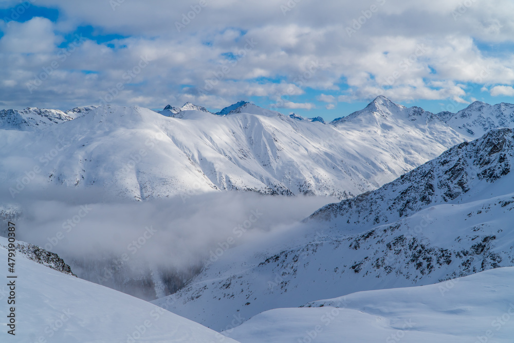 Amazing alpine panoramic view in Livigno, Italy with clouds below snowy peaks