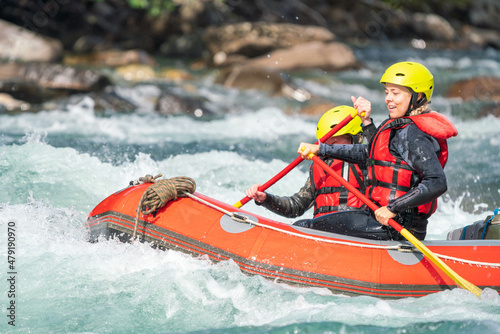 Two girls enjoying themself with river rafting water sports. Smiles, recreation and happiness concept. Removed logos.