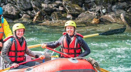 Two girls enjoying themself with river rafting water sports. Smiles  recreation and happiness concept. Removed logos.