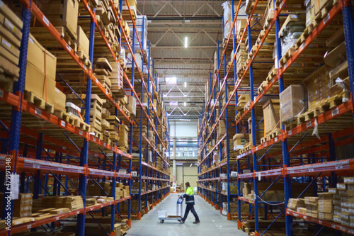 Blur warehouse background. Warehouse worker taking package in the shelf in a large warehouse in a large warehouse.