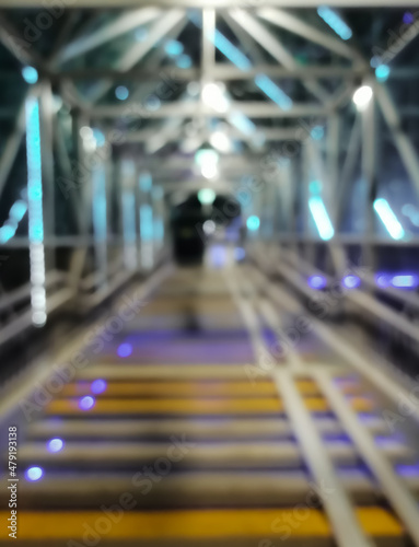 Blurred pedestrian bridge at night. LED illumination. Abstract background with night lights. Defocused.