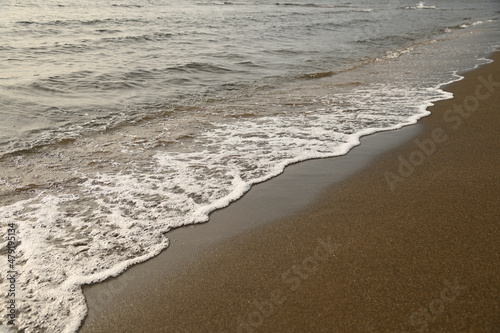 砂浜に打ち寄せる穏やかな波と白い泡