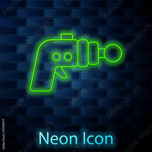 Glowing neon line Ray gun icon isolated on brick wall background. Laser weapon. Space blaster. Vector