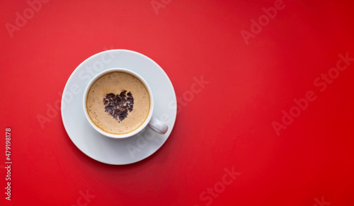 Obraz na plátně A mug of coffee with a chocolate heart on the foam stands on a monochromatic red