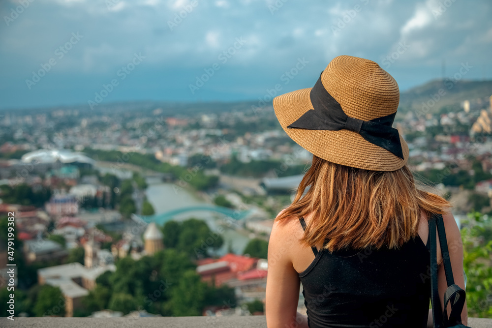 Woman in sun hat looking from panorama at Tbilisi city