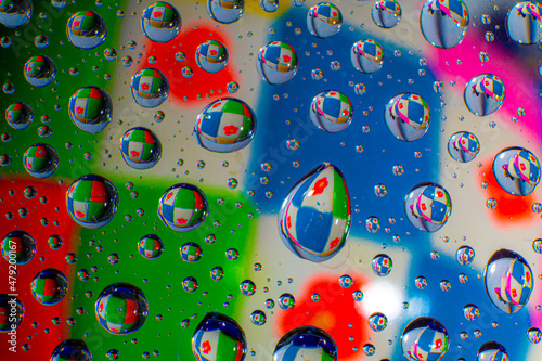 Water droplets on a glass in form of lenses with a colourful background. Wallpaper for screen. Abstract background.