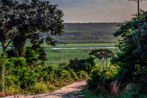 Estrada de terra, horizonte verde e rio