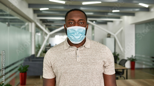 Black man in medical mask look at camera in office