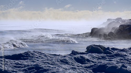 Waves crash against the icy Lake Michigan shoreline with steam coming off the water in subzero temperatures. Taken at Gillson Beach in Wilmette, Illinois. photo