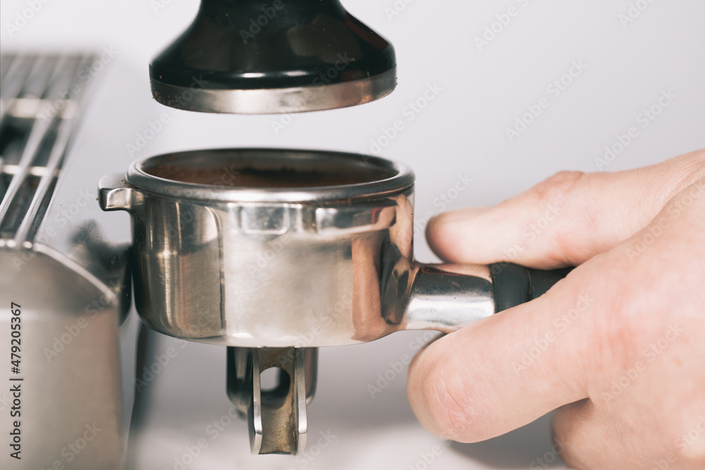 Pressing ground coffee in handle for extracting in espresso machine Pressing ground coffee in handle for extracting in espresso machine