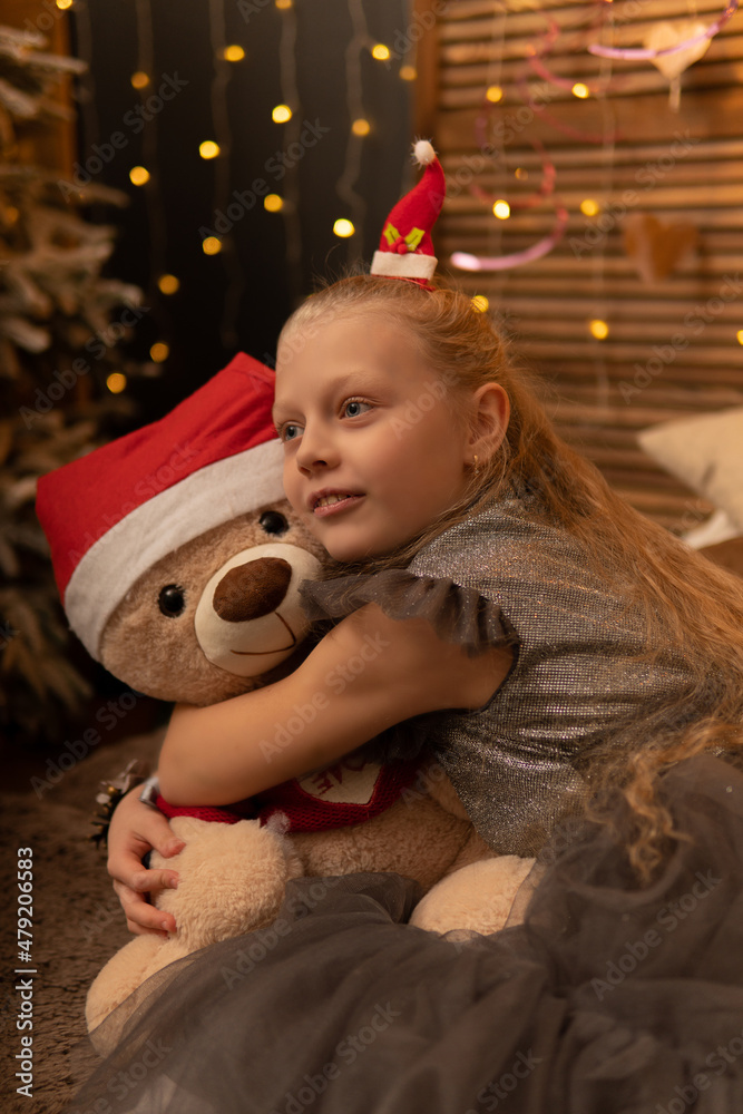 A girl hugs a bear toy in a Christmas cap bear Christmas kid girl happy, for female smiling from teddy white fun, joy baby. Gift bed holding, hug wake