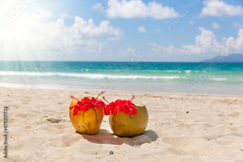 Two coconut cocktails on white sand beach