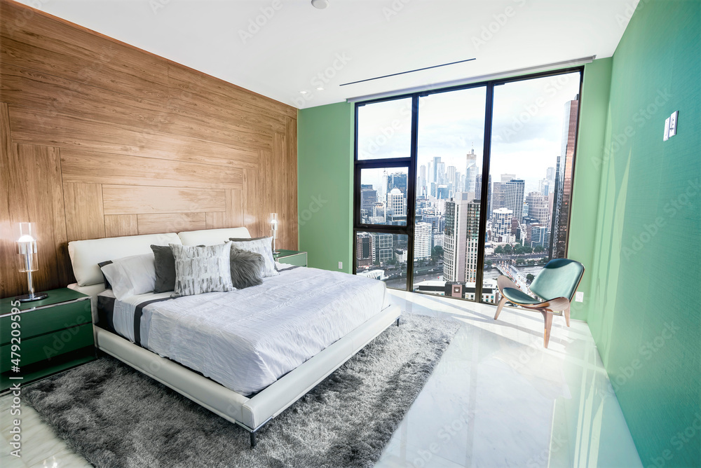 Fototapeta premium Modern and contemporary bedroom in Melbourne with views of the financial district of the city. Condo or Hotel accommodation. Pale green, maple and gray colors.