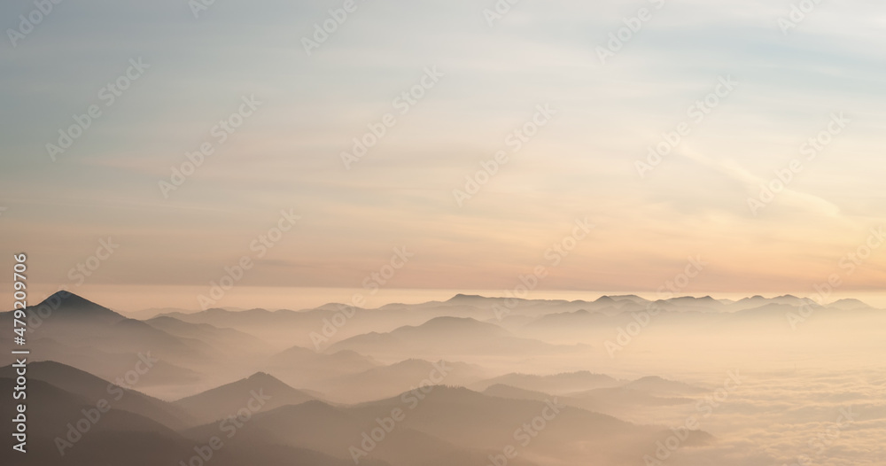 Mountain range with visible silhouettes through the morning colorful fog. Mountain range with visible silhouettes through the morning colorful fog.