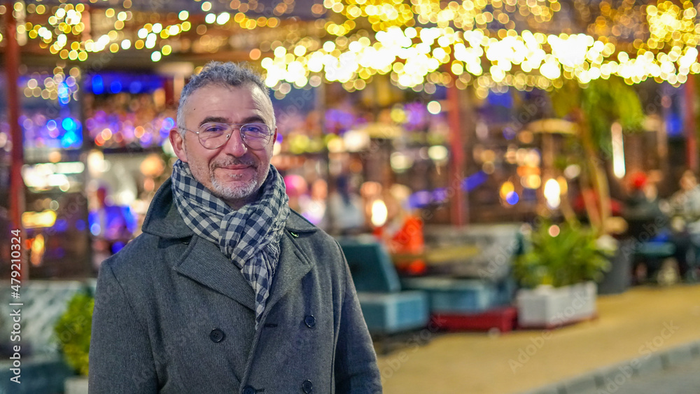 Hombre de mediana edad con abrigo y bufanda con boké de fondo de luces amarillos Hombre de mediana edad con abrigo y bufanda con boké de fondo de luces amarillos