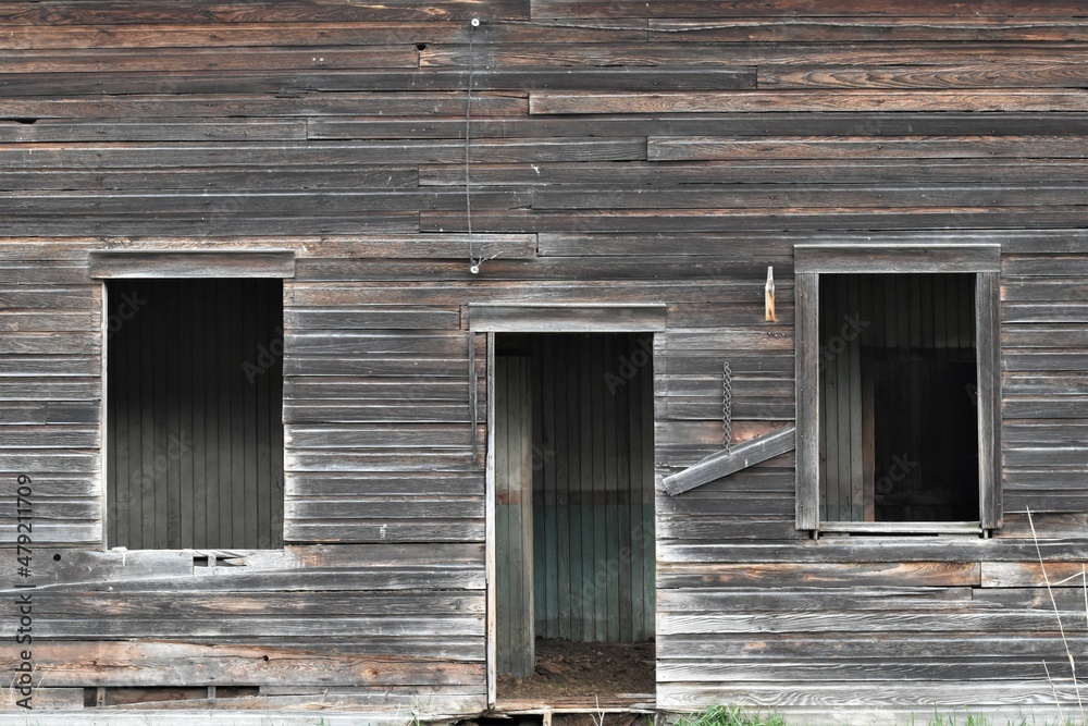 Exterior view of an old abandoned house with rough weathered wood, empty door and windows visible. Exterior view of an old abandoned house with rough weathered wood, empty door and windows visible.