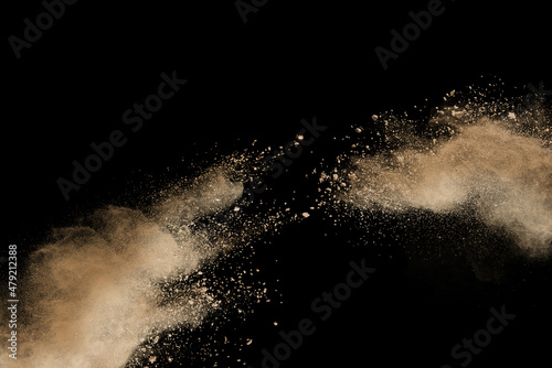 Freeze motion of brown color powder exploding on black background. 