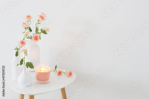 pink roses in white vase on  table on background white wall