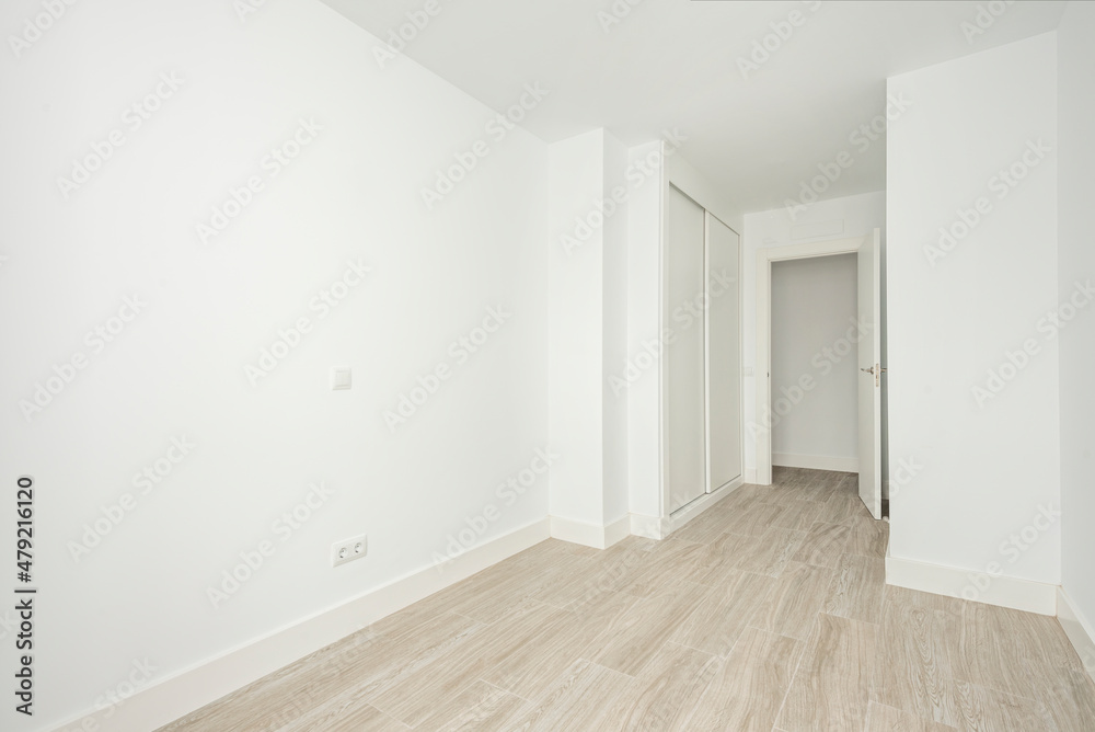 Fototapeta premium Empty white room with built-in wardrobes and wooden-like ceramic floors