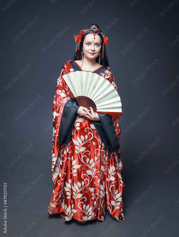 Beautiful young woman in red traditional Chinese costume with hand fan Beautiful young woman in red traditional Chinese costume with hand fan