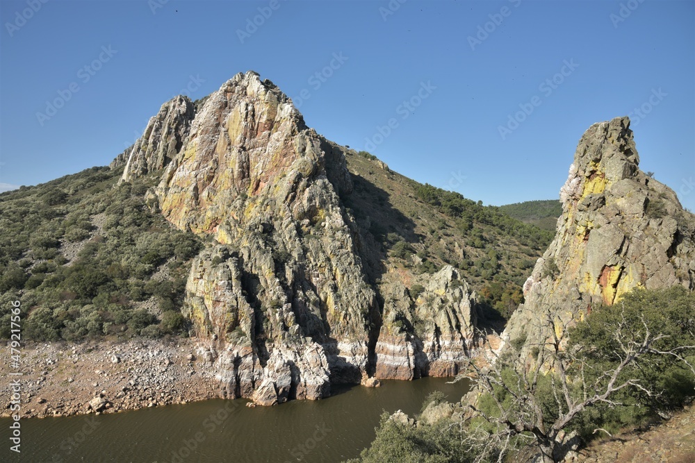 Forbidding cliffs at the confluence gorge of Tajo and Tietar rivers, encrusted in salt, rising from a typical central Spanish arid oak dehesa, seen from Salto Del Gitano at Monfragüe National Park