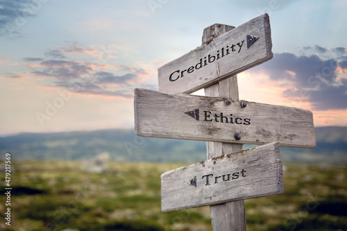 credibility ethics trust text quote on wooden signpost outdoors during sunset. photo