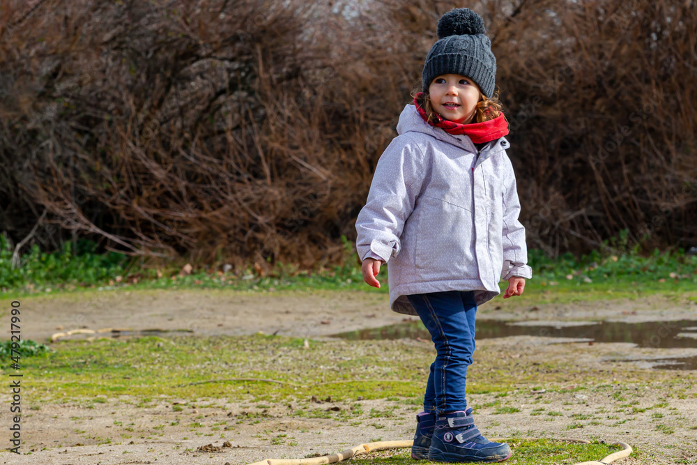 Little girl with hat and red scarf playing in the field. Children with winter clothes Little girl with hat and red scarf playing in the field. Children with winter clothes