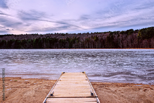 Winter at Bowman Lake State Park in Chenango County in Upstate NY.  Dock looks out over a frozen lake with snow blown over it.