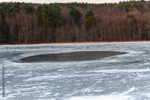 Winter at Bowman Lake State Park in Chenango County in Upstate NY.  A large hole in the middle of the lake has not yet frozen solid.  Open water as ice on lake is still freezing. photo