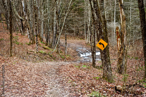 Winter at Bowman Lake State Park in Chenango County in Upstate NY.  I traffic sign in the middle of the wooded path.  Sign for future snowmobilers to head after snow falls. photo