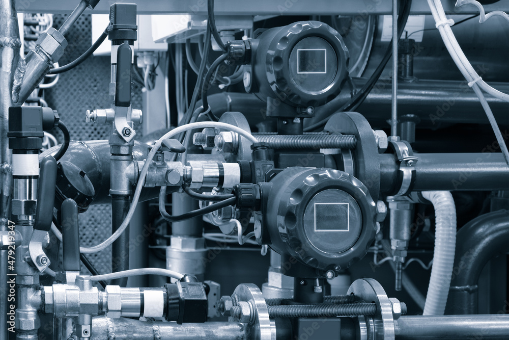 Close up of manometer, pipe, flow meter, water pumps and valves of heating system in a boiler room