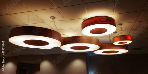 A group of lights in an office. Circular lights hang from the ceiling of this office waiting room.