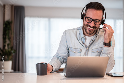 Cheerful young adult businessman entrepreneur freelancer making online video call. Portrait of man working from home office providing call support call center operator.