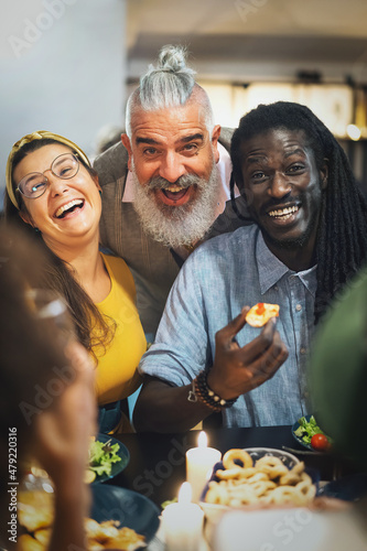 Obraz na plátne multi-ethnic group of friends smiling looking at camera while they're dining tog