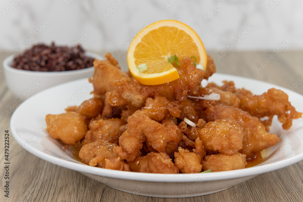 Breaded orange chicken crispy on the outside with sliced citrus twist