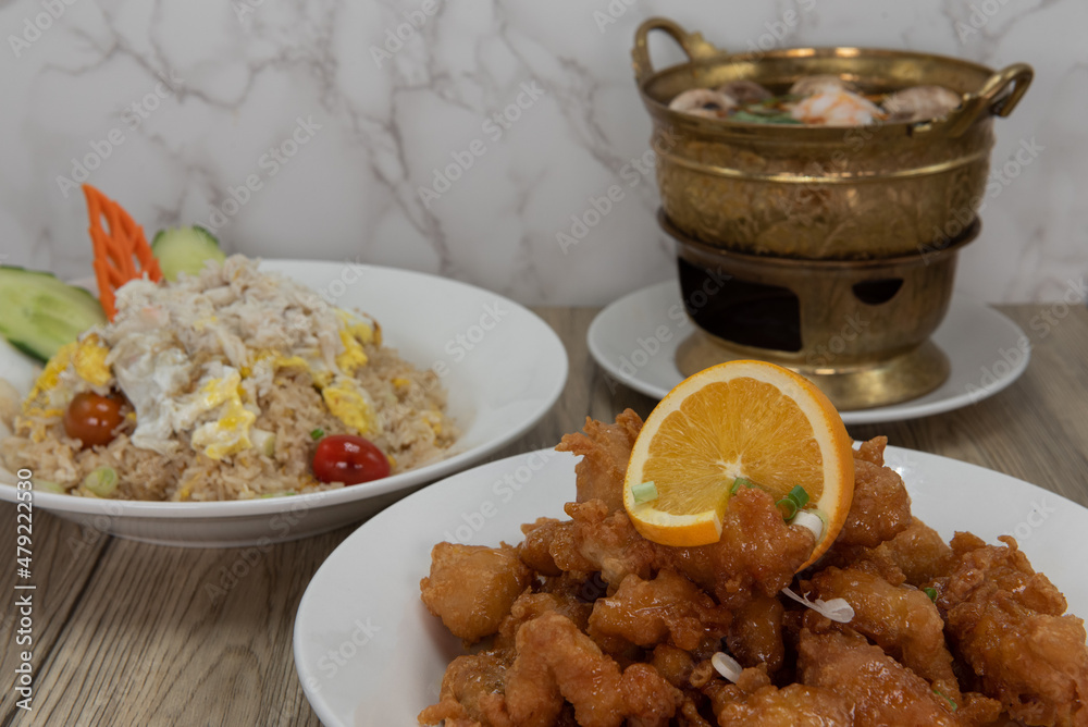 Pile of breaded orange chicken with orange slice on the front of a