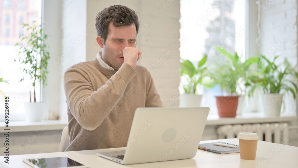 Man Coughing while using Laptop in Office Man Coughing while using Laptop in Office