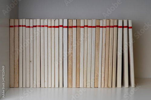Pile of books with blank spine on a white shelf