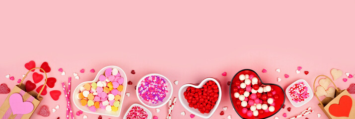 Valentines Day candy bottom border with a selection of sweets. Top down view on a pink paper banner background with copy space.