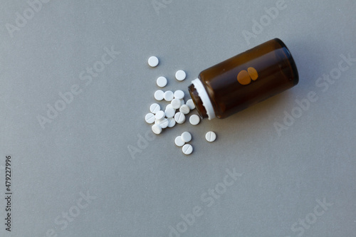 White pills (medicine) spilling out of a brown bottle