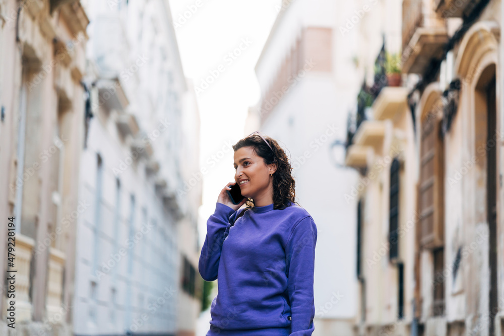 Fototapeta premium Cheerful man talking on smartphone on street
