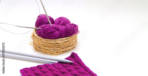 Balls of colored knitting threads and knitting needles on a white background. Needlework and stress relief