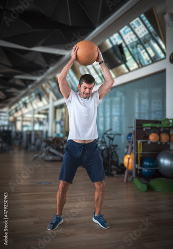 Man exercising in the gym with a heavy medicine slam ball