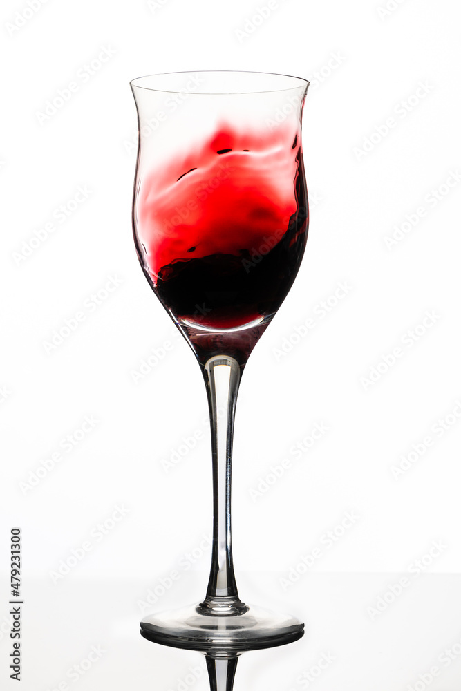 Swirl or movement of liquid in a glass of red wine. White background, vertical orientation. Concept of movement, elegance. Swirl or movement of liquid in a glass of red wine. White background, vertical orientation. Concept of movement, elegance.