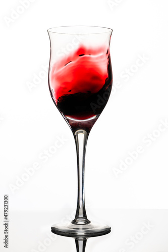 Swirl or movement of liquid in a glass of red wine. White background, vertical orientation. Concept of movement, elegance.