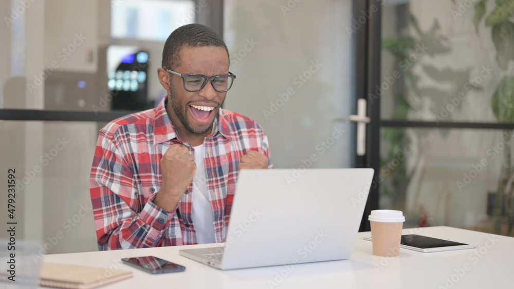 African Man Celebrating Success while using Laptop African Man Celebrating Success while using Laptop