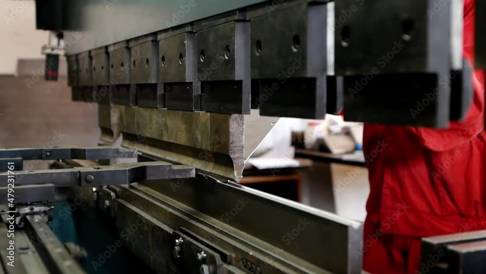 Close-up of a worker bends a sheet of metal using a metalworking machine. Heavy industry plant for the production of metal products. Close-up of a worker bends a sheet of metal using a metalworking machine. Heavy industry plant for the production of metal products.