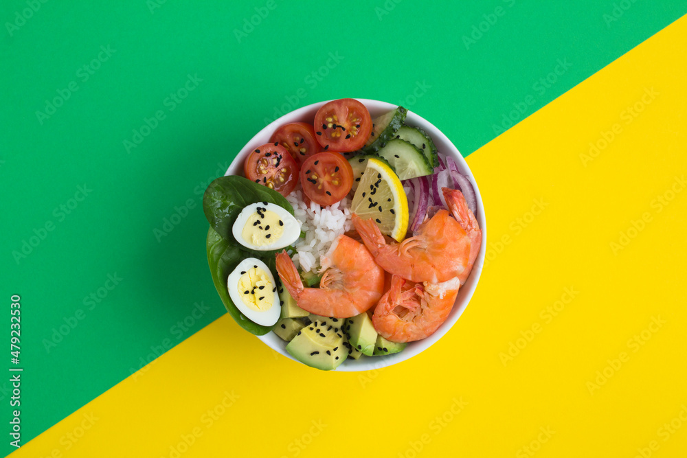 Top view of poke bowl with shrimps, rice and vegetable on the colored background. Close-up. Top view of poke bowl with shrimps, rice and vegetable on the colored background. Close-up.